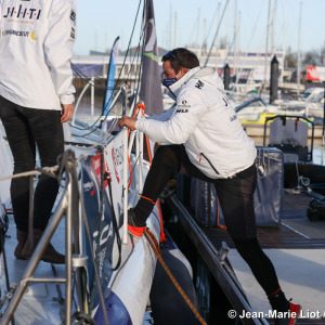 Clément Giraud qui grimpe à bord de son IMOCA pour quitter les pontons